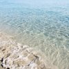 Acqua cristallina che lambisce la riva sabbiosa.