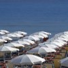 Spiaggia con file di ombrelloni bianchi.