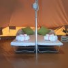 Interno di una tenda con letti e cuscini verdi.