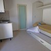 Stanza con letto singolo, angolo cottura e porta bianca.