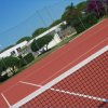 Campo da tennis con rete in primo piano.