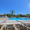 Piscina con sdraio e cielo azzurro.
