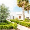 Edificio bianco con giardino e palme.