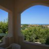 Vista su colline verdi e mare da una terrazza con arco.
