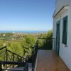 Balcone con vista sul mare e colline verdi.