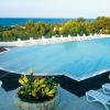 Piscina con lettini bianchi e vista mare.