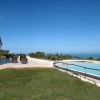 Piscina a sfioro con vista sul mare, affiancata da un patio moderno.