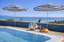 Piscina con ombrelloni a strisce blu e bianche, vista panoramica.