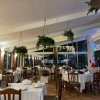 Ristorante elegante con tavoli apparecchiati e piante appese.