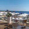 Terrazza con tavoli bianchi e vista mare soleggiata.