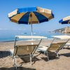 Due lettini e ombrelloni blu su una spiaggia sabbiosa.