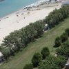 Spiaggia sabbiosa con mare blu e alberi vicino ad edifici.