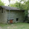 Edificio in pietra con tetto spiovente tra alberi.