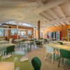 Interno ristorante con tavoli verdi e bianchi, decorazioni soffitto.