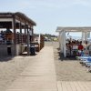 Spiaggia con passerella e ristoranti all'aperto.