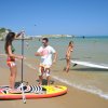 Persone con tavole da paddle sulla spiaggia.