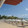 Spiaggia sabbiosa con lettini e ombrelloni bianchi.