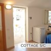 Stanza con finestra, frigo bianco e letto.