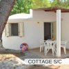 Cottage bianco con veranda e tavolo esterno.