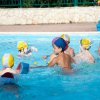Bambini giocano in piscina con cappelli colorati.