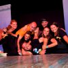 Gruppo di giovani sorride su un palco.