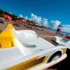 Pedalò gialli e spiaggia con ombrelloni arancioni.