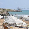 Spiaggia con ombrelloni e scogli sullo sfondo.