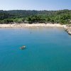 Baia con acqua turchese e barca gialla in lontananza.