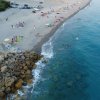 Spiaggia con ombrelloni colorati, bagnanti e mare limpido.