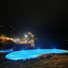 Piscina illuminata di notte con vista sul mare.