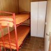 Letto a castello con struttura rossa e materassi arancioni in una stanza con armadio bianco.