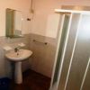 Un bagno con doccia, specchio rettangolare e lavandino bianco.