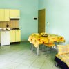 Cucina e soggiorno con pareti azzurre, mobili gialli e tavolo con tovaglia floreale.