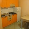 Cucina con mobili arancioni, tavolo e sedie.