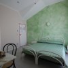 Letto matrimoniale fronte muro verde in camera d'albergo.