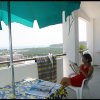 Donna seduta su un balcone con vista mare.