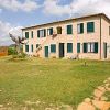 Una casa in mattoni con persiane verdi, circondata da un giardino e un vialetto di pietre.