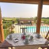 Tavolo apparecchiato su balcone con vista su piscina e campo aperto.