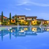 Piscina illuminata di sera con riflessi, villette sullo sfondo e cielo crepuscolare.