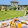 Colazione con frutta, dolci e succo vista su villa in pietra. Ampio prato verde circostante.