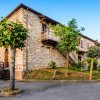 Edificio in pietra con balconi in legno, alberi e vialetti di fronte.