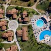 Complesso residenziale con villette, rotonda e piscine dall'alto.
