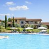 Piscina all'aperto con ombrelloni, sedie a sdraio e un edificio con tetto in tegole sullo sfondo.