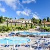 Piscine circolari e rettangolari con lettini e ombrelloni bianchi.