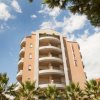 Un edificio moderno con balconi e palme in primo piano.
