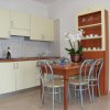 Cucina con mobili chiari, tavolo in legno e sedie, fiore al centro.
