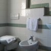 Bagno semplice con wc, bidet, lavandino e asciugamano bianco su un portasciugamani.