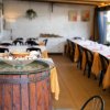 Ristorante con tavoli apparecchiati e barile decorativo.