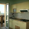 Cucina vista mare con mobili chiari, fornelli e cappa. Porta aperta verso balcone.