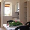 Cucina luminosa con tavolo bianco, sedie nere e fiori. Finestre aperte.